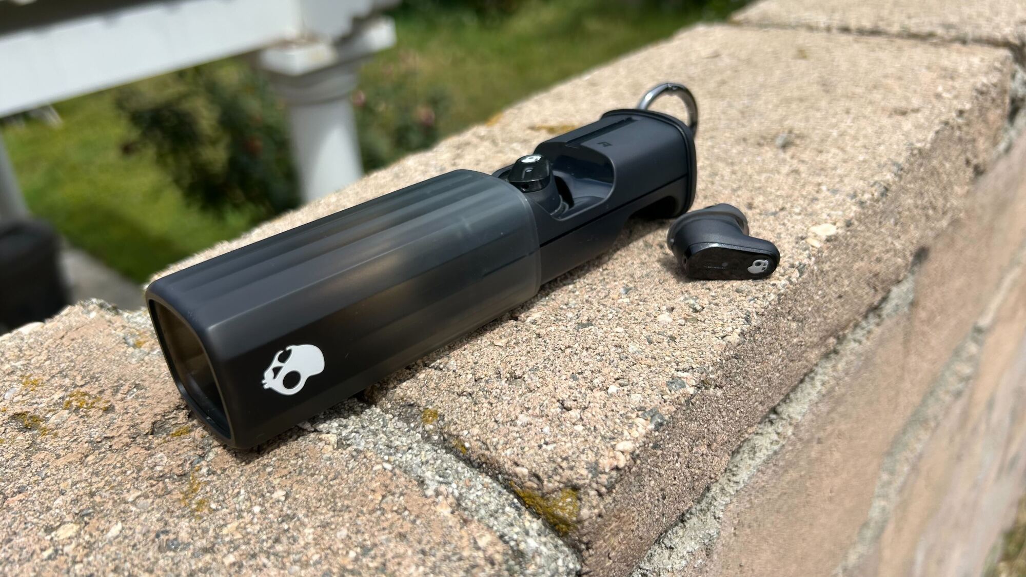 skullcandy case with earbuds out of it on a wall
