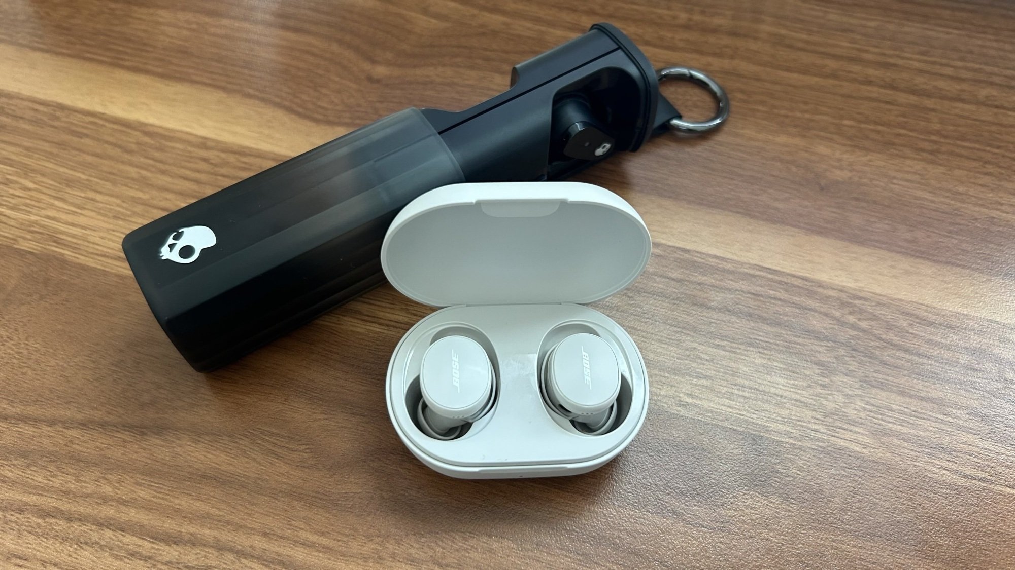 black skullcandy earbuds case opened up behind open bose earbuds case