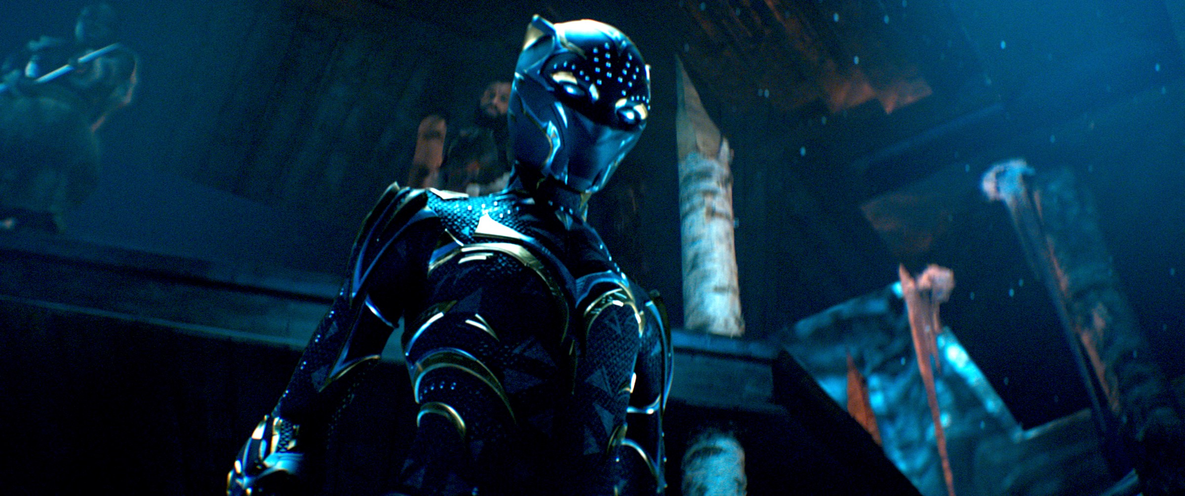 Shuri in her gold-streaked Black Panther suit, standing in a dark throne room, in Black Panther: Wakanda Forever
